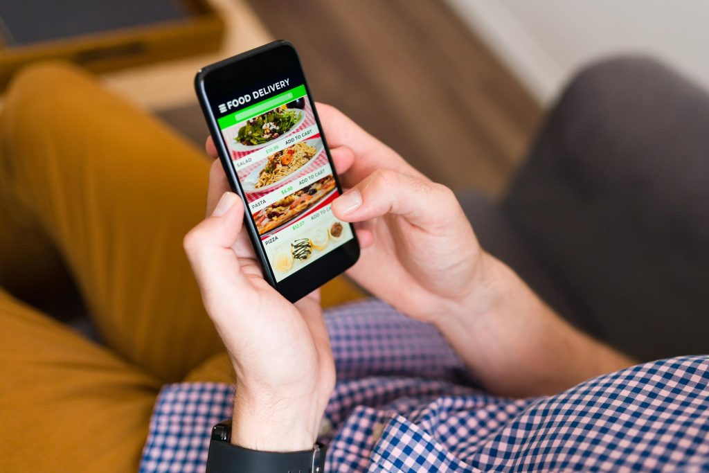 Mężczyzna zamawia jedzenie online w restauracji za pomocą telefonu.