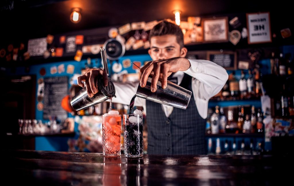 Barman przygotowuje koktajle dla gości w lokalu przy barze.