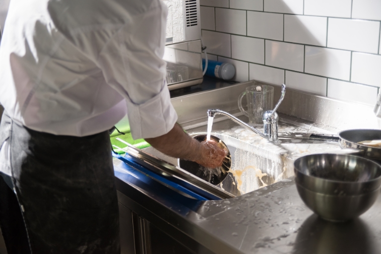 Mycie naczyń na małym zapleczu gastronomicznym w restauracji.