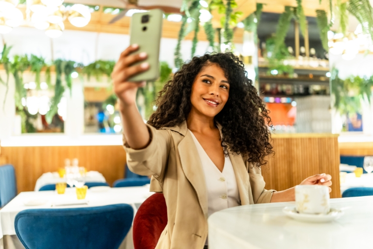 Kobieta robi selfie w letnim ogródku w restauracji.